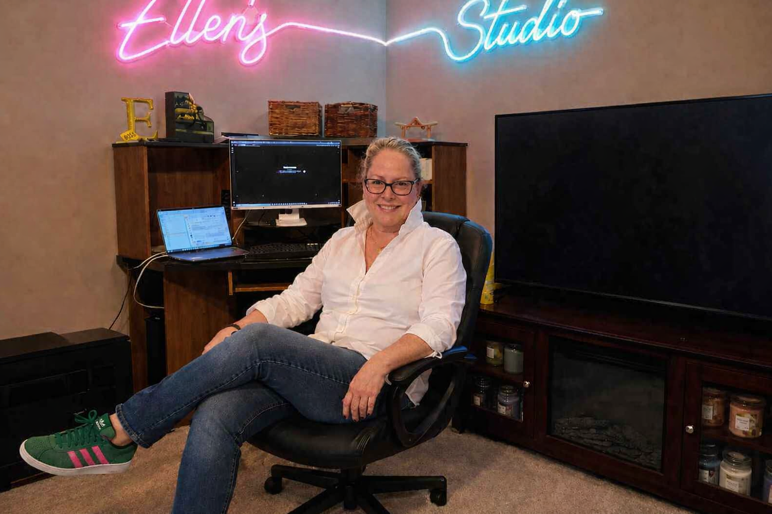 Ellen McKay seated in her creative studio under an 'Ellen's Studio' neon sign