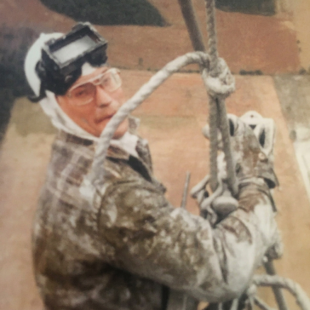 Original 1970s photograph of a tower climber wearing a welding hood and gloves